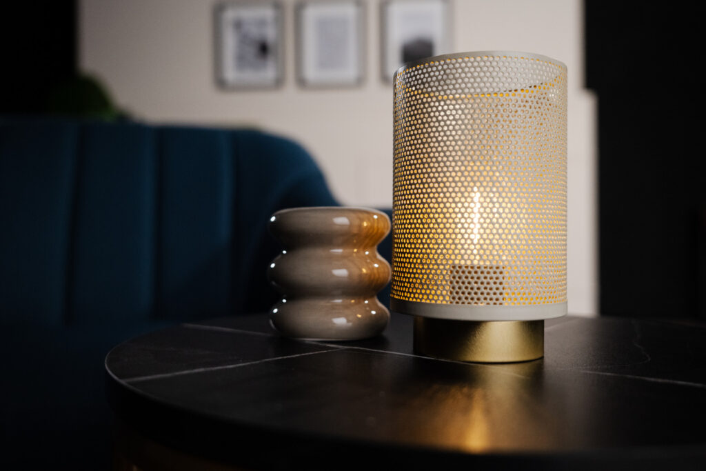 Détail d'une lampe tamisée et d’un petit objet déco sur une table noire