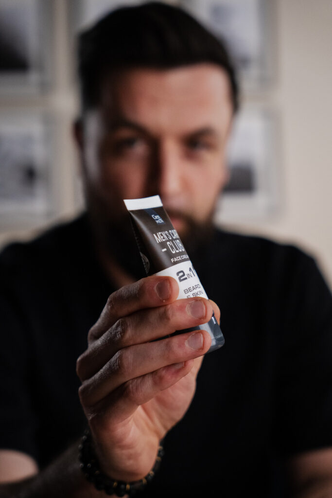 Main d’un homme tenant un tube de cosmétique dans le décor La Parenthèse