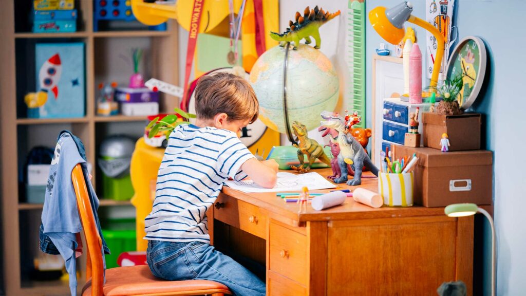 tournage-chambre-enfant-bts Enfant dessinant dans une chambre décorée avec des jouets et une ambiance colorée.