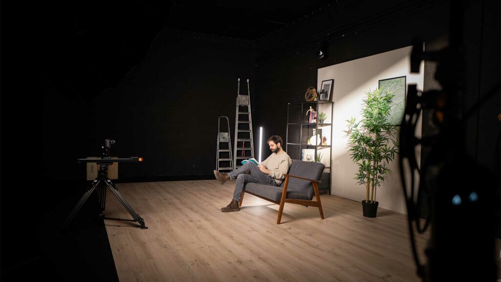 tournage-decor-vide-bts Lecture de script sur un canapé dans un décor lumineux et vide en cours d’installation.
